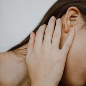 Close-up of a person cupping their ear with their hand near the side of the head